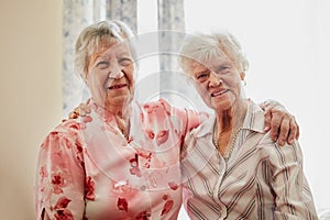 Good old friends make the best of friends. Portrait of two happy elderly women embracing each other at home.