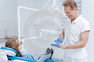 Good qualified dentist putting on special gloves