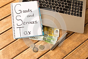 Good service and tax . Laptop, pen, coins, banknotes on wood ba