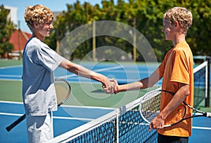 Good sportsmanship. a two young tennis players shaking hands over the net.