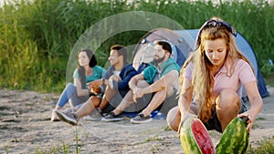 Good summer day for a group of teen people multiracial they have a picnic time lady cut a big watermelon for her friends