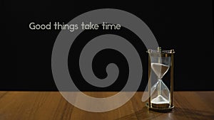 Good things take time, popular expression about patience, sandglass on table