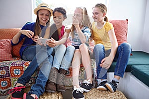 Good times with friends make the best memories. a group of teenage friends using a cellphone together.