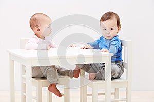 Good times with my new friend. Shot of two adorable little babies sitting together at a table.