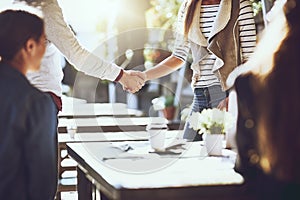 Good to meet you. colleagues shaking hands during a meeting at an outdoor cafe.