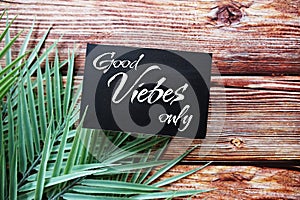 Good vibes only text message top view on wooden background with green leaf decoration