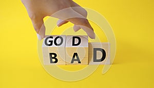 Good vs Bad symbol. Businessman Hand turns cubes and changes word Bad to Good. Beautiful yellow background. Business and Good vs