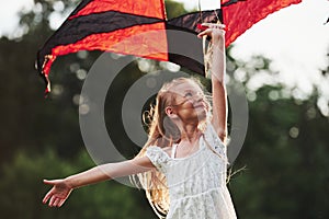 Good wind. Happy girl in white clothes have fun with kite in the field. Beautiful nature