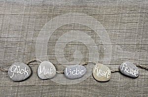 Good wishes wooden background with stones and german text for lu