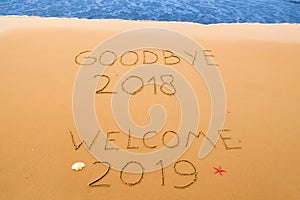 Goodbye 2018 and welcome 2019 written in the sand