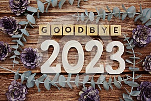 Goodbye 2023 alphabet letters with flower decorate on wooden background