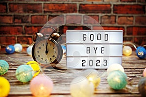 Goodbye 2023 text in light box with alarm clock and LED cotton balls decoration