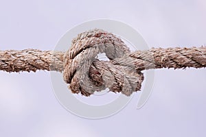 Tied knot on a white rope isolated on white background. Macro photo