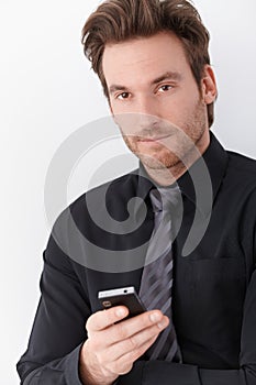 Goodlooking businessman holding mobile phone