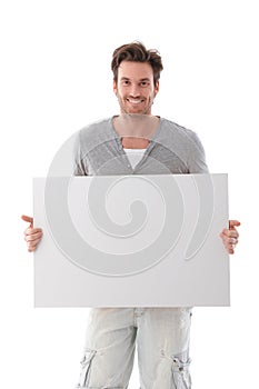 Goodlooking man holding white panel smiling