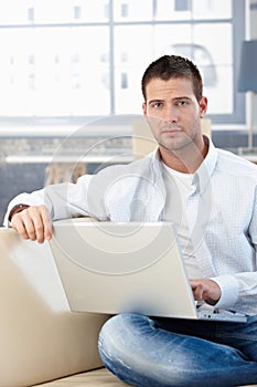 Goodlooking man working at home on laptop