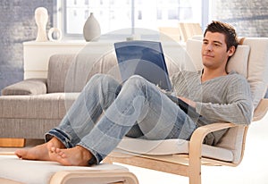 Mladý muž relaxačné na prenosný počítač 