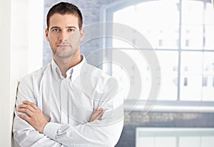 Goodlooking young man standing arms crossed