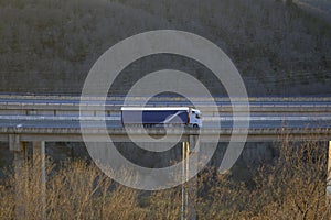 Goods truck crossing a highway bridge at sunset horizontal