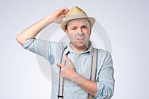 Goofy man in summer hat is worried and shocked because of sweating stain.