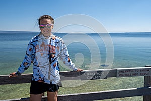 Goofy tourist woman wearing a tacky souviner sweatshirt poses at Lakeshore Geyser in Yellowstone