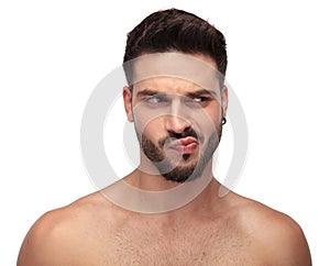 Goofy undressed guy with beard looking away curious