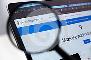 Google Maps Platform logo enlarged through a magnifying glass on a laptop screen
