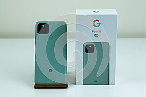Google Pixel 5 in Sorta Sage color next to its box.