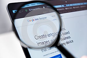 Google Web Designer logo enlarged through a magnifying glass on a laptop screen