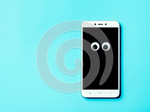 Googly eyes on smartphone, copy space