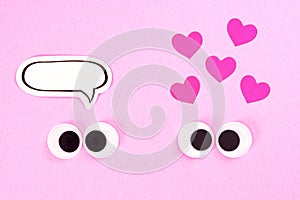 Googly eyes. Strange pair of cross-eyed lovers on rose background with some small hearts and copy space for thoughts