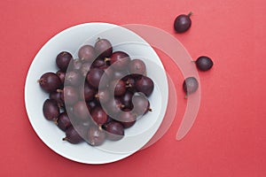 Gooseberries in a bowl on red background with space for copy text.