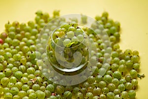 Gooseberries in a transparent jar on a yellow background.