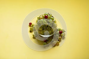 Gooseberries in a transparent jar on a yellow background.