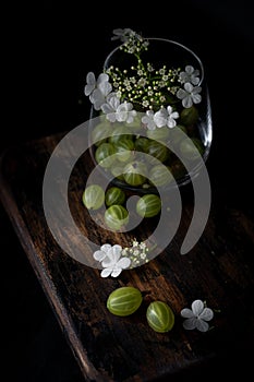 Gooseberry and flowers in glass cup on a wooden Board, still life with berries