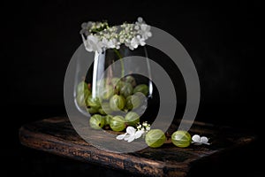 Gooseberry and flowers in glass cup on a wooden Board, still life with berries