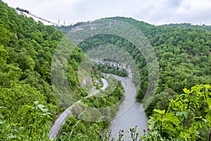 A gorge in the mountains with a suspension bridge over it. Skybridge suspension bridge over a precipice on a cloudy day. SkyPark,