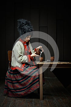 Gorgeouns young woman in ukrainian traditional costume holding clay jug of milk