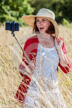 Gorgeous 50s woman making a selfie on mobile phone on stick