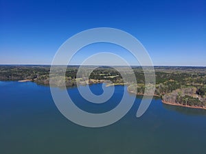 A gorgeous aerial shot of a vast blue lake with lush green and autumn colored trees reflecting off the lake at Lake Horton Park