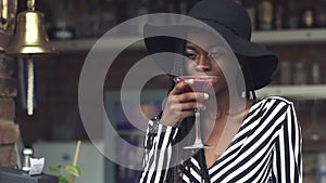 Gorgeous african american business lady drinking cocktail at bar with fancy interior