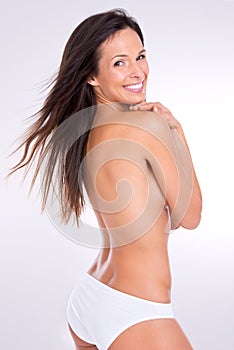 Gorgeous in anything. Studio portrait of a beautiful topless woman looking back over her shoulder.