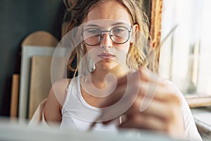 Gorgeous artist female standing in front of the camera painting something in her art studio. A professional young woman painter in