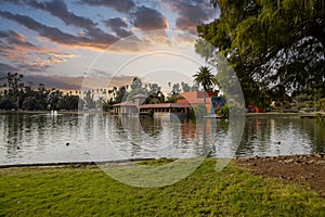 A gorgeous autumn landscape at Lincoln Park with a lake surrounded by lush green palm trees and plant, an orange building