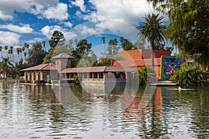 A gorgeous autumn landscape at Lincoln Park with a lake surrounded by lush green palm trees and plant, an orange building