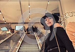 Gorgeous beautiful model with hat posing on escalator