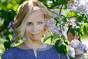 Gorgeous beautiful young blond girl near lilac bush