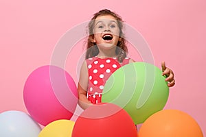 Gorgeous Birthday baby girl, 4 years kid hugging colorful balloons,rejoicing looking up, isolated over pink background with copy