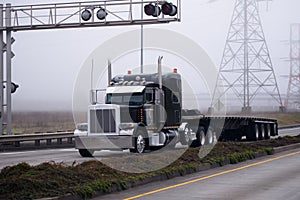 Gorgeous black big rig semi truck flat bed trailer devided road