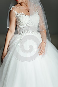 Gorgeous, blonde bride in white luxury dress is getting ready for wedding. Morning preparations. Woman putting on dress.